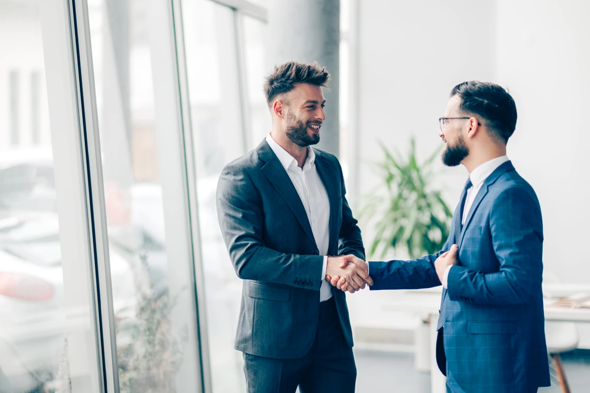 Ein Handschlag zwischen zwei Geschäftspartnern, der das Vertrauen symbolisiert, das durch Informationssicherheit im B2B-Umfeld entsteht.
