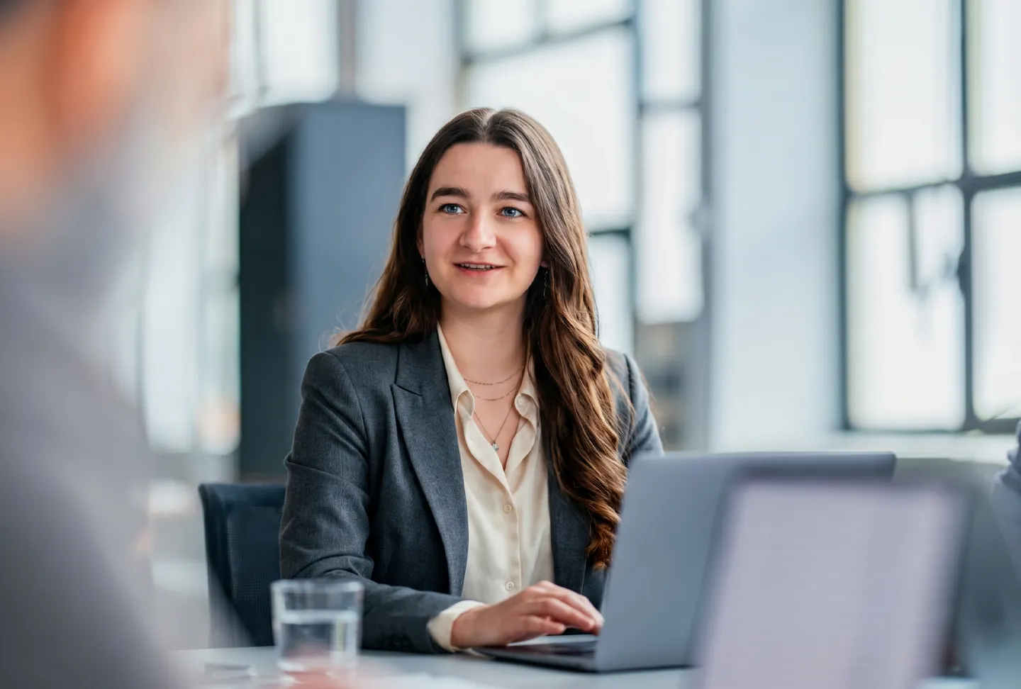 Mitarbeiterin arbeitet konzentriert am Laptop und bespricht eine Aufgabenstellung im modernen Büro – strukturierte Planung und professionelle Projektarbeit.